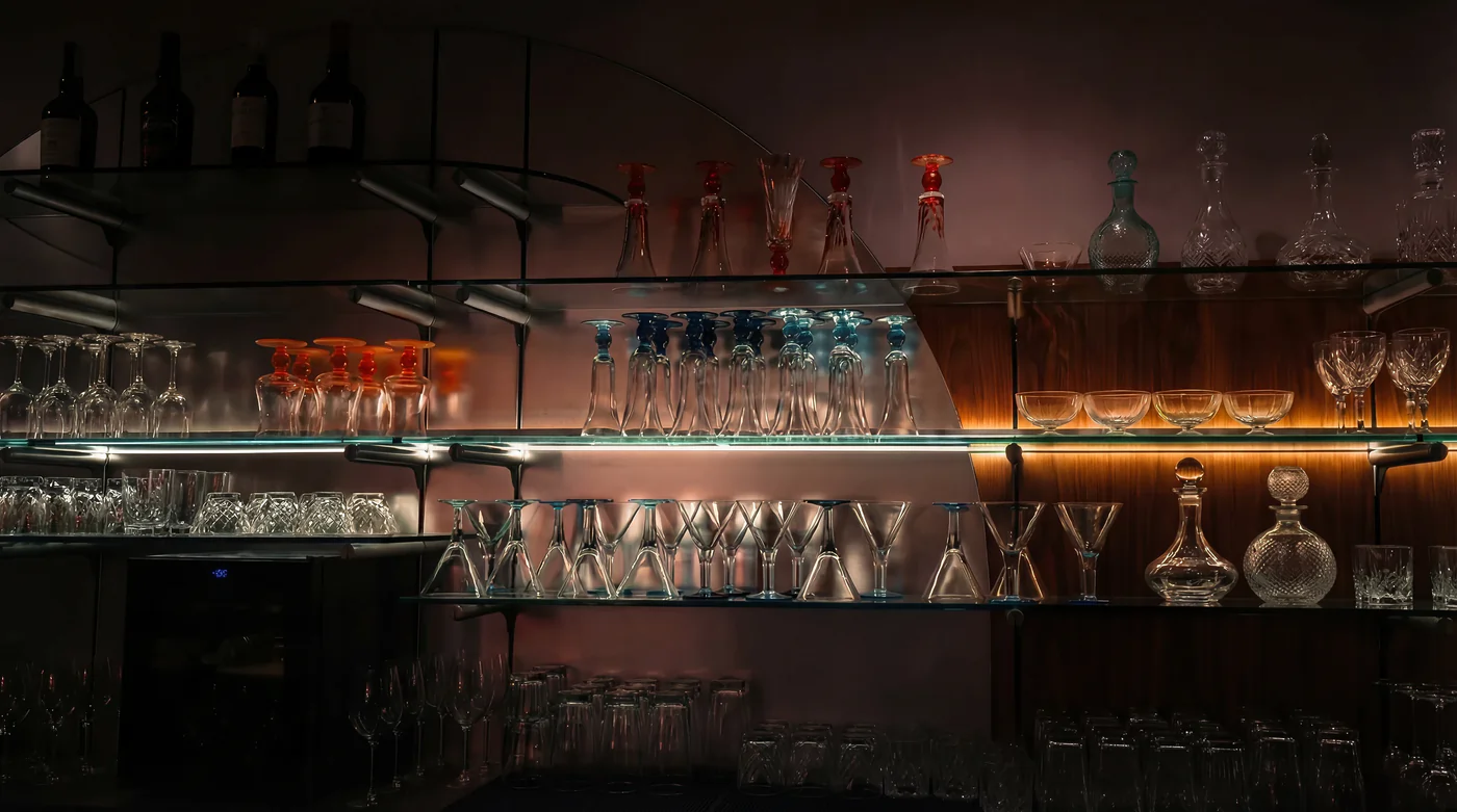 ADRIAGEL® Glaskollektion – Exklusive mundgeblasene Eisgläser, Dessertschalen und Karaffen in stimmungsvoller Bar-Atmosphäre mit eleganter Regalbeleuchtung
